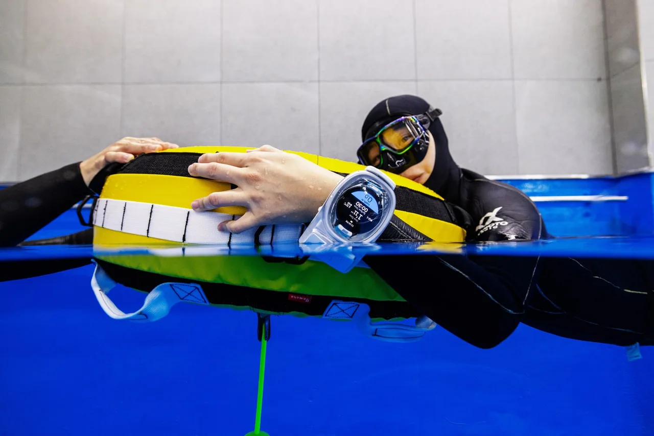 Praticante de apneia apoiada em uma boia de treino na piscina, com o WatchDive no pulso