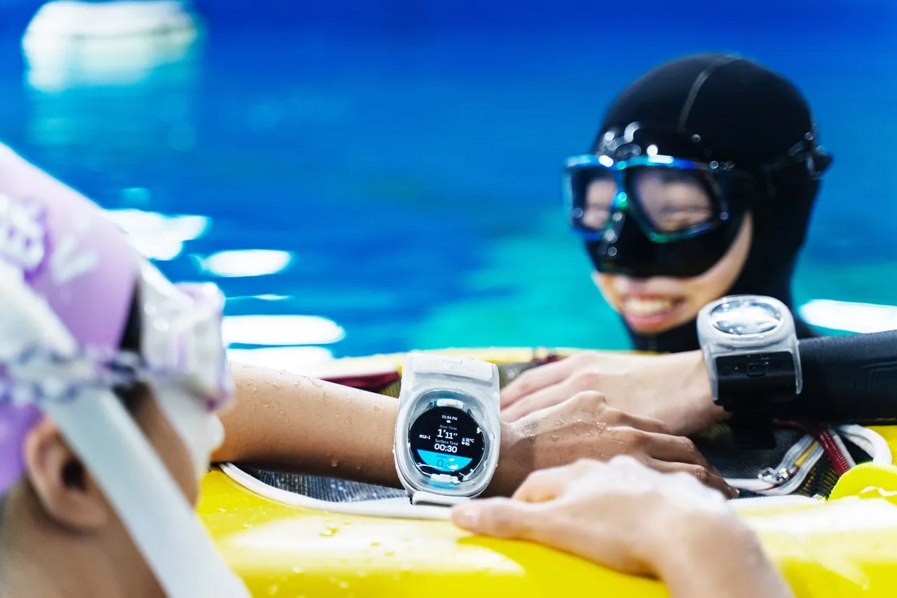 Mergulhadores na superfície de uma piscina, apoiados em uma boia, com o WatchDive no pulso
